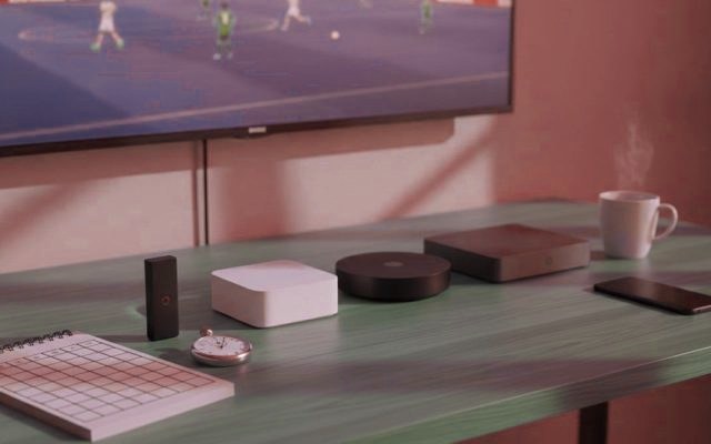 Five streaming devices, a notebook scoring grid and a stopwatch in front of a TV showing a football match
